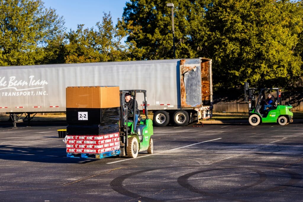 Forklift operators loading pallets onto a truck outdoors on a sunny day. Efficient warehouse logistics in action.